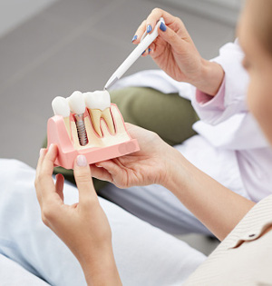 Dummy model showing dental implant screw fitted into a model jawbone in Worcester & Central, MA